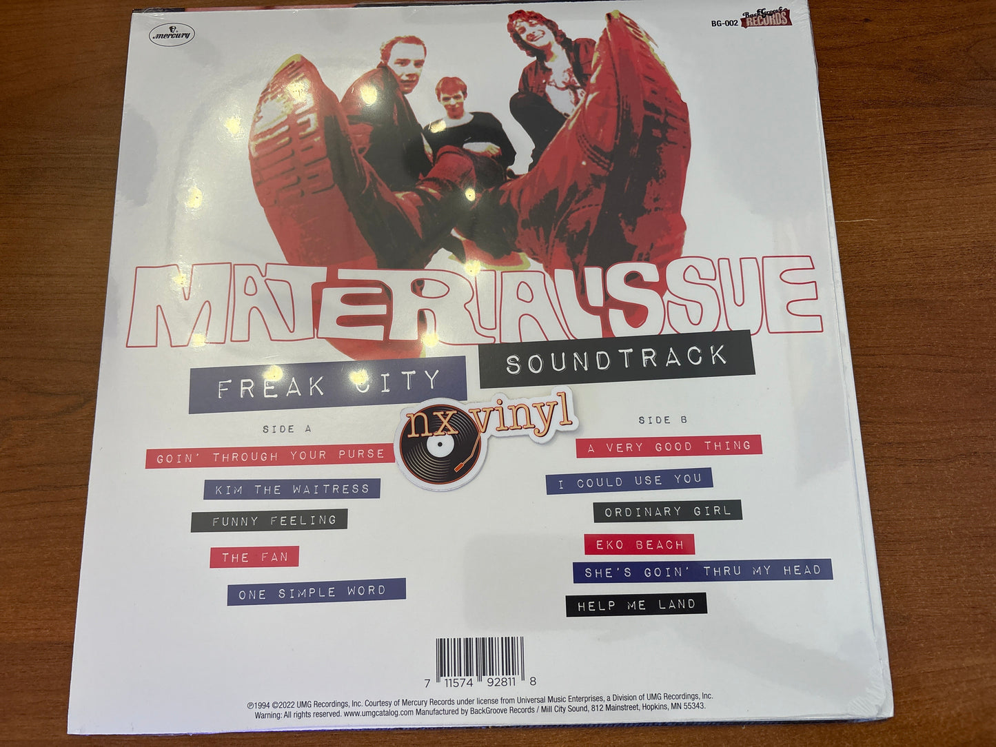 Vinyl record cover with album art and text on a wooden surface