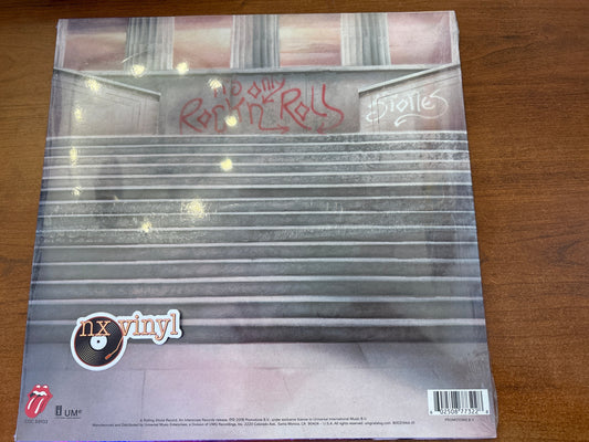 Vinyl record cover with 'Rolling Stones' and 'nx vinyl' branding on a wooden surface