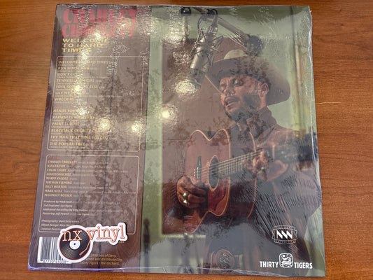 Vinyl record cover with a person playing guitar on a wooden surface