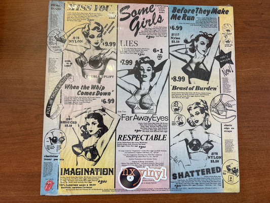 Vinyl record cover with vintage-style advertisements and graphics on a wooden surface