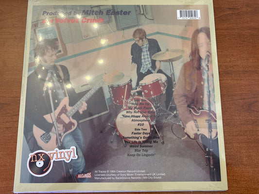 Vinyl record cover with band members and text on a wooden surface