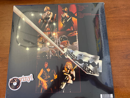 Vinyl record sleeve with band images and a razor blade on a wooden surface