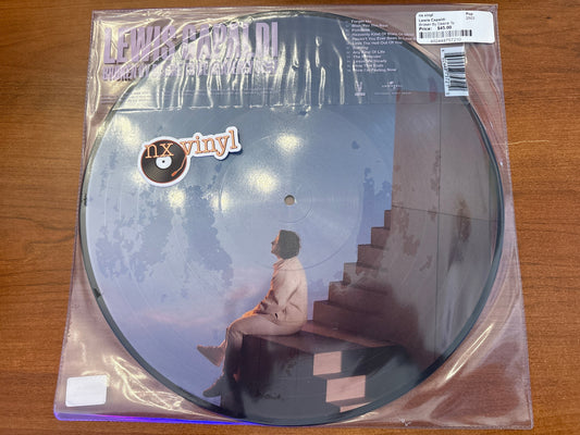 Vinyl record in clear packaging with a person sitting on stairs, 'nx vinyl' logo visible.