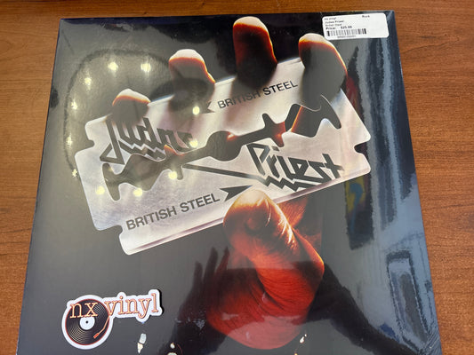 Vinyl record cover with 'Judas Priest' design on a wooden surface