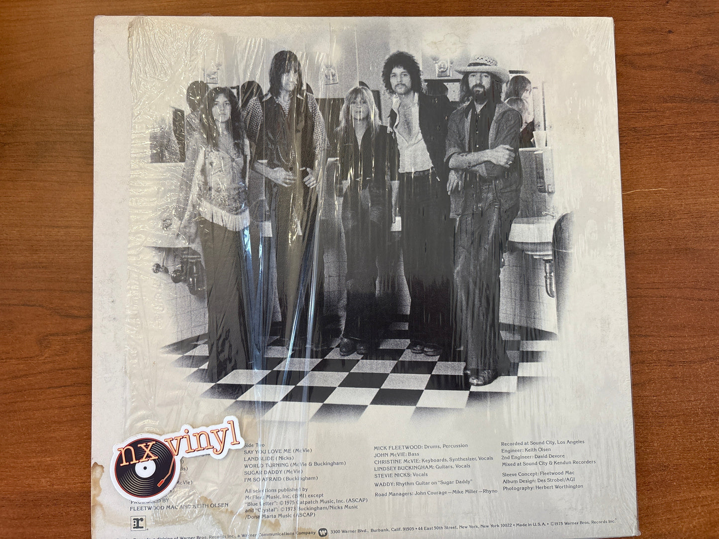 Vintage album cover with a group of people on a checkered floor, featuring the 'nx vinyl' logo.