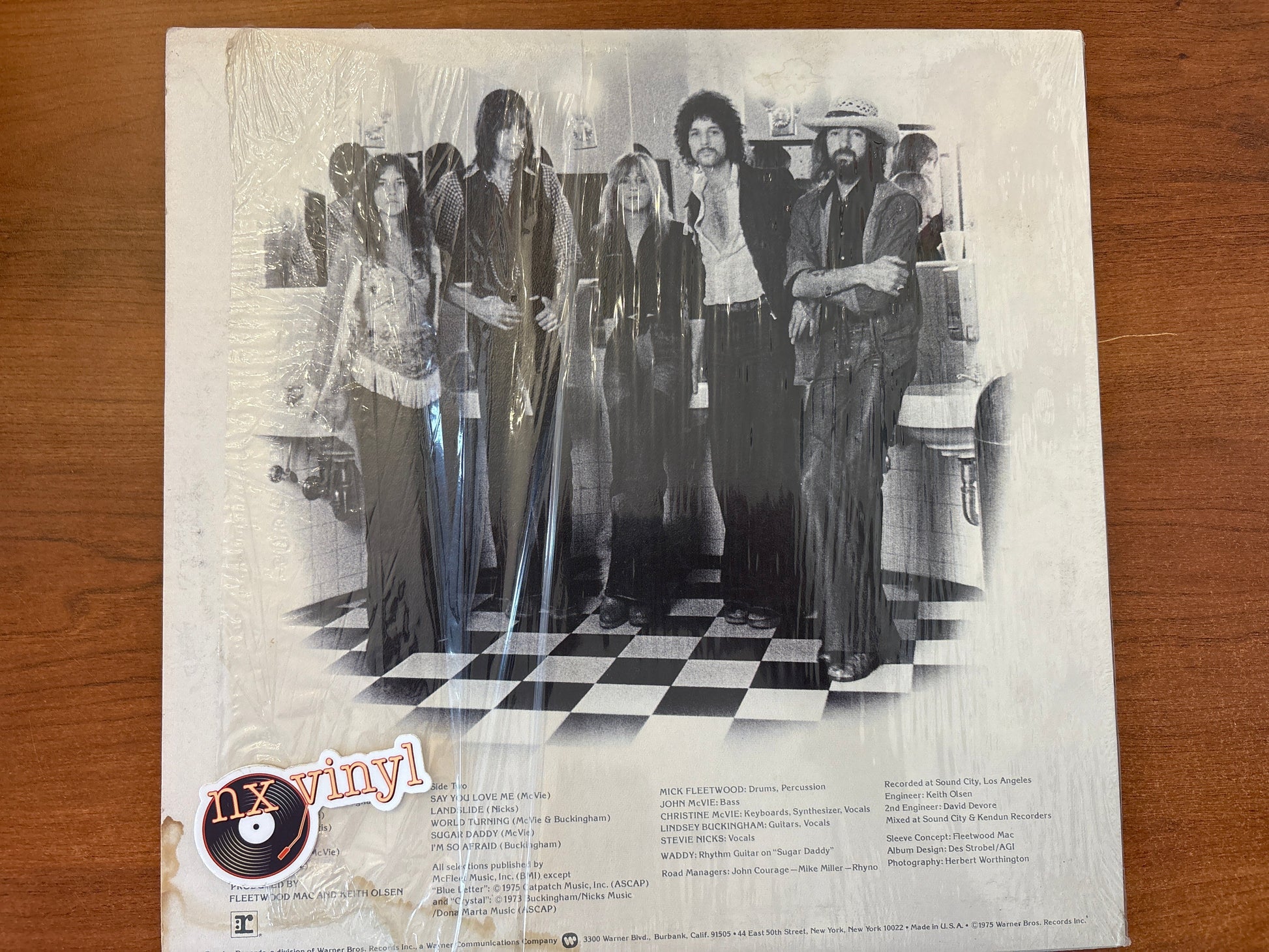 Vintage album cover with a group of people on a checkered floor, featuring the 'nx vinyl' logo.