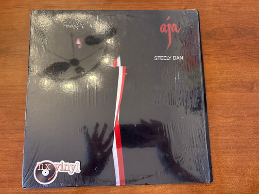 Vinyl record cover for 'Aja' by Steely Dan on a wooden surface