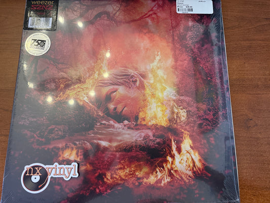 Vinyl record with a cover featuring a face and flames, on a wooden surface.