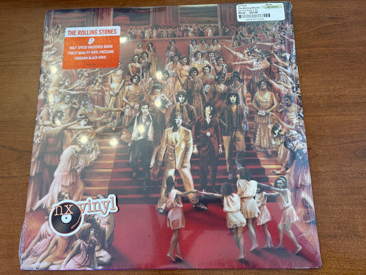 Vinyl record cover with a colorful illustration of people on a red carpet, featuring 'The Rolling Stones' on a wooden surface.