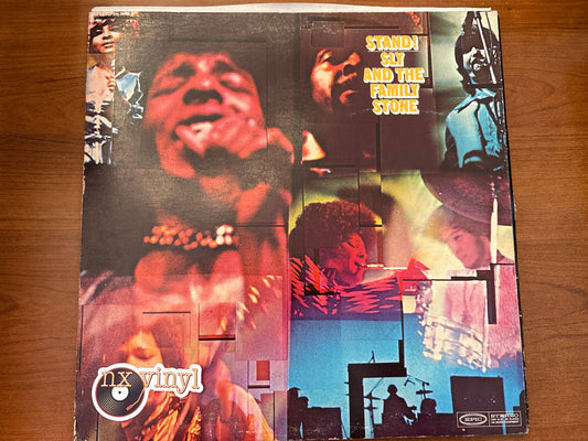 Vinyl record cover with multiple images of a person and text on a wooden surface