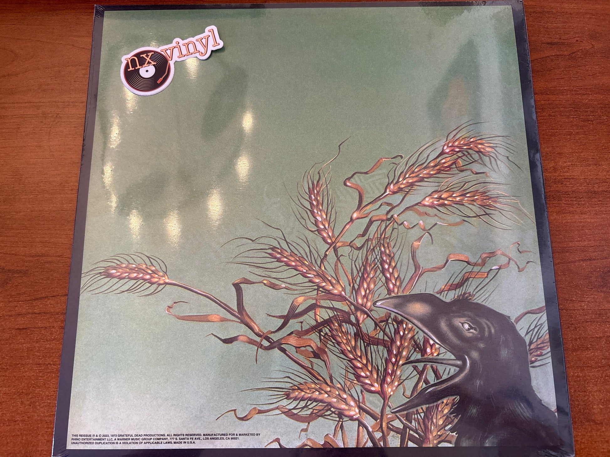Vinyl record cover with a crow and wheat design on a green background