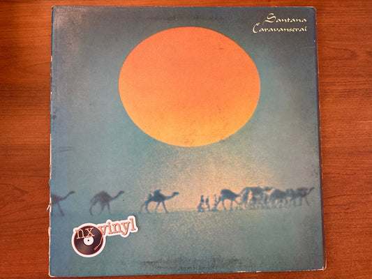 Vinyl record cover with a sunset and camel caravan design on a wooden surface